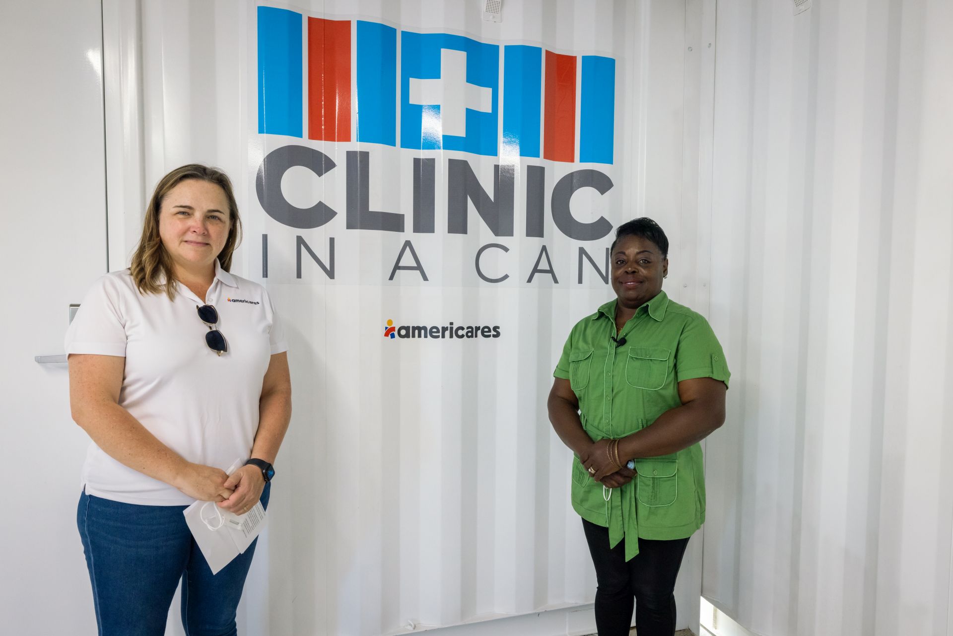Two staff members stand outside the Clinic in a Can donated by Americares