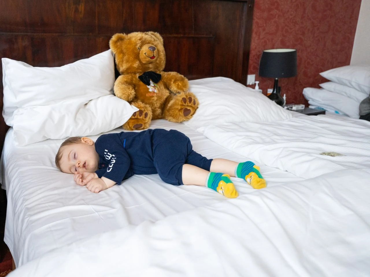 Timofy sleeps on a bed with his bear in a hotel in Krakow, Poland
