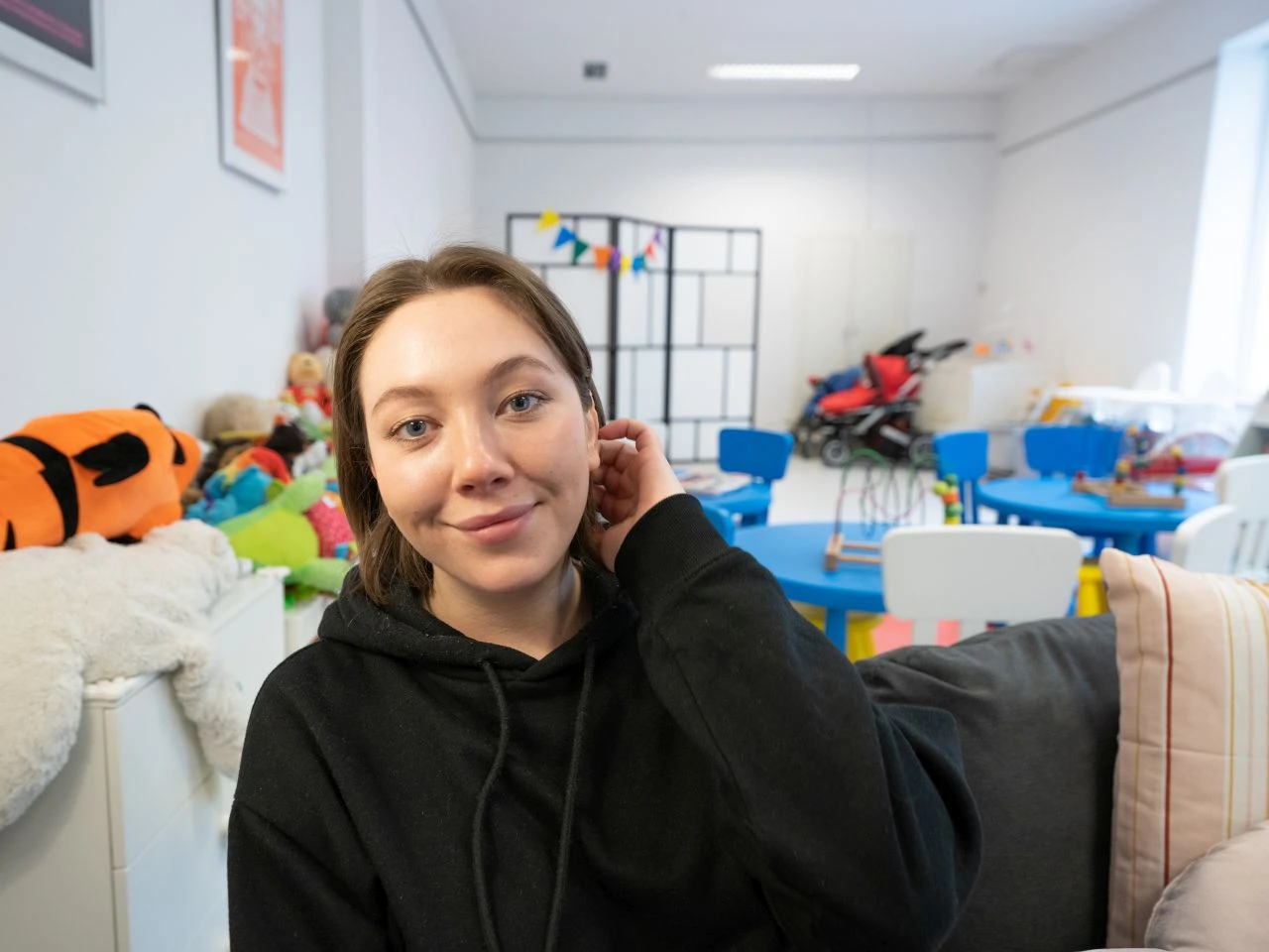Rita, from Odessa, Ukraine, poses for a photo at the Jewish Community Center with toys in the background in Krakow, Poland