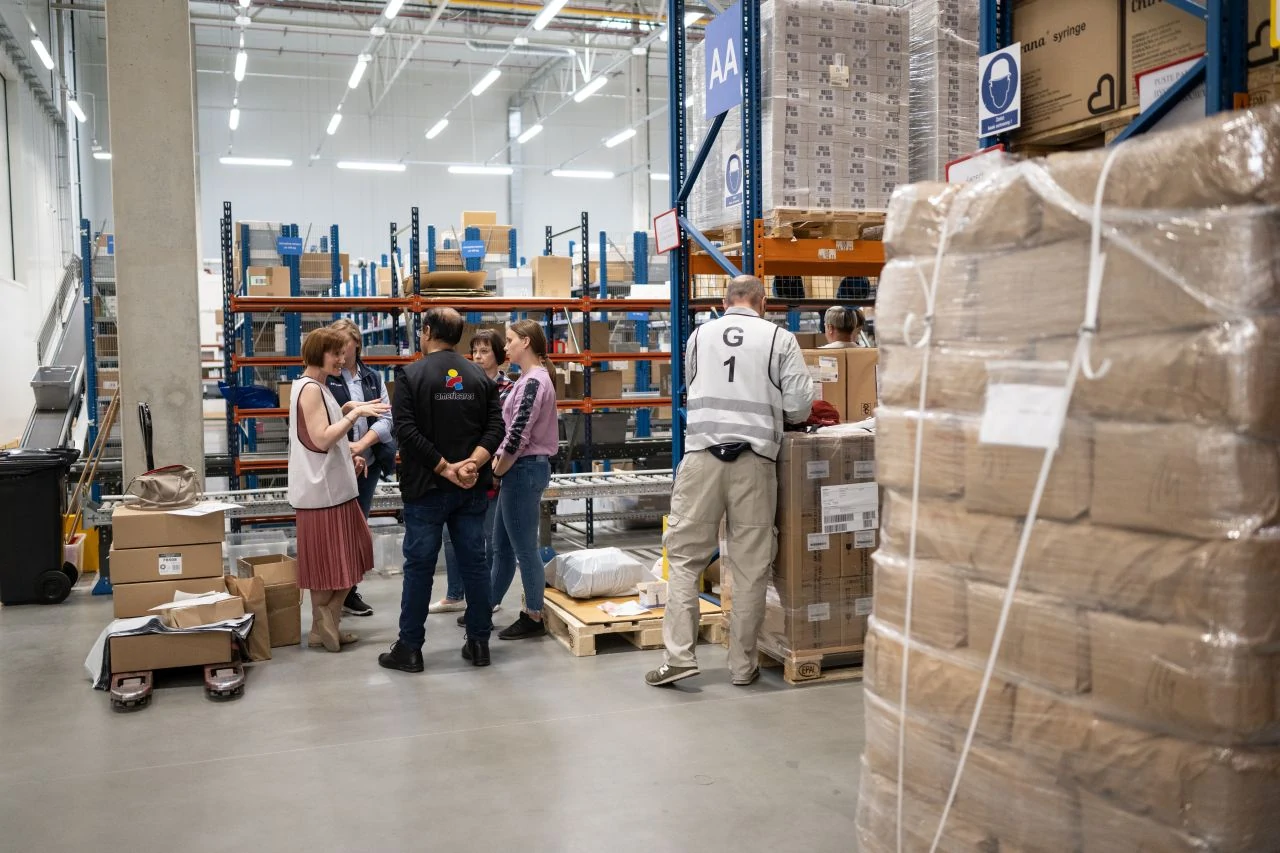 An Americares relief worker confers with 3 local workers in a warehouse handling shipments of relief supplies