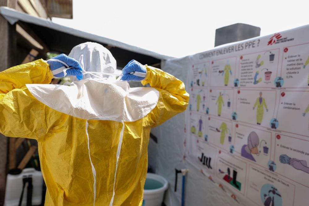 A health care worker dons personal protective equipment