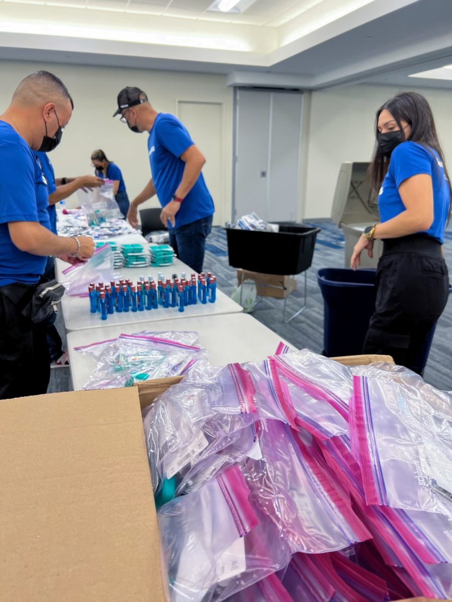 Americares staff in blue shirts assemble hygiene kits on long table