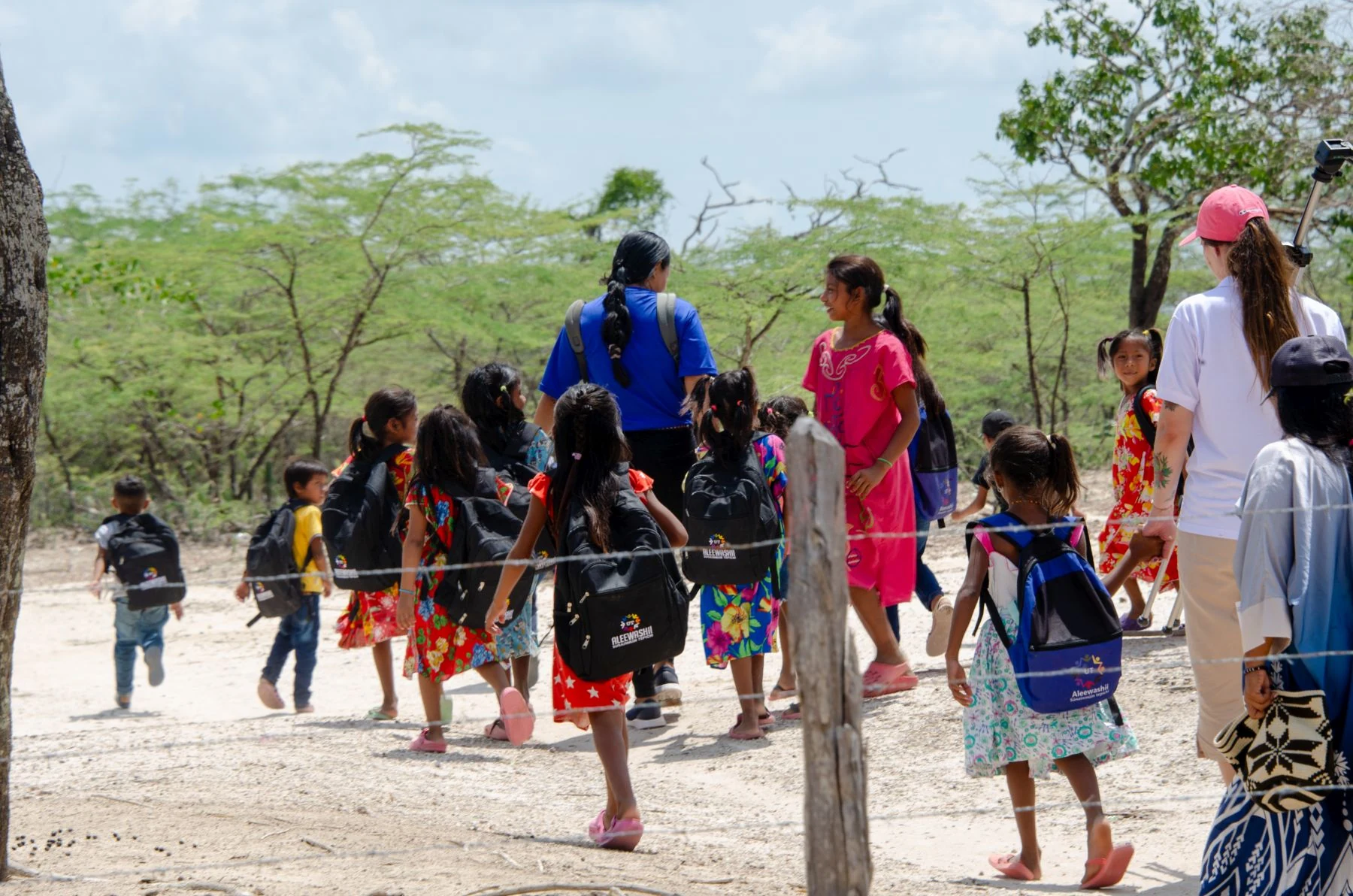 Group of Wayuu Children with backpacks walking with backs to camera with 3 adults