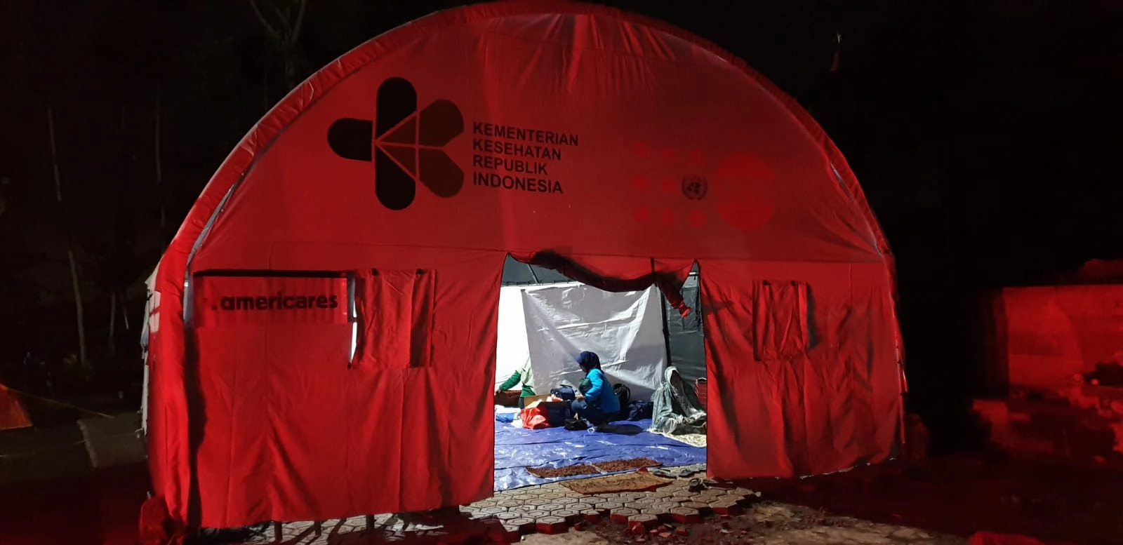 Red tent for health care with americares logo on outside with woman inside