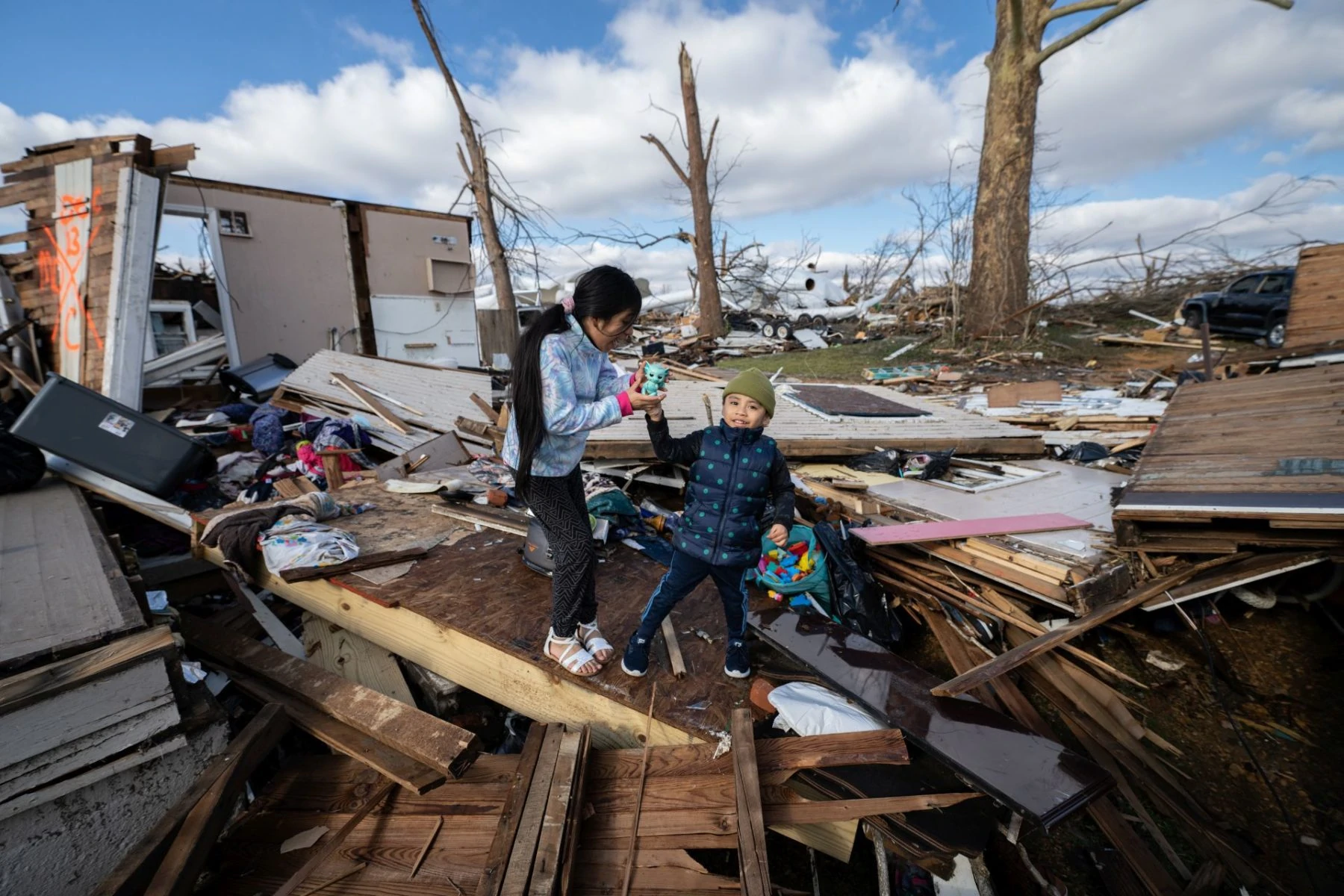 Two children play in the ruins of their family home where they survived a devastating tornado in Mayfield KY.