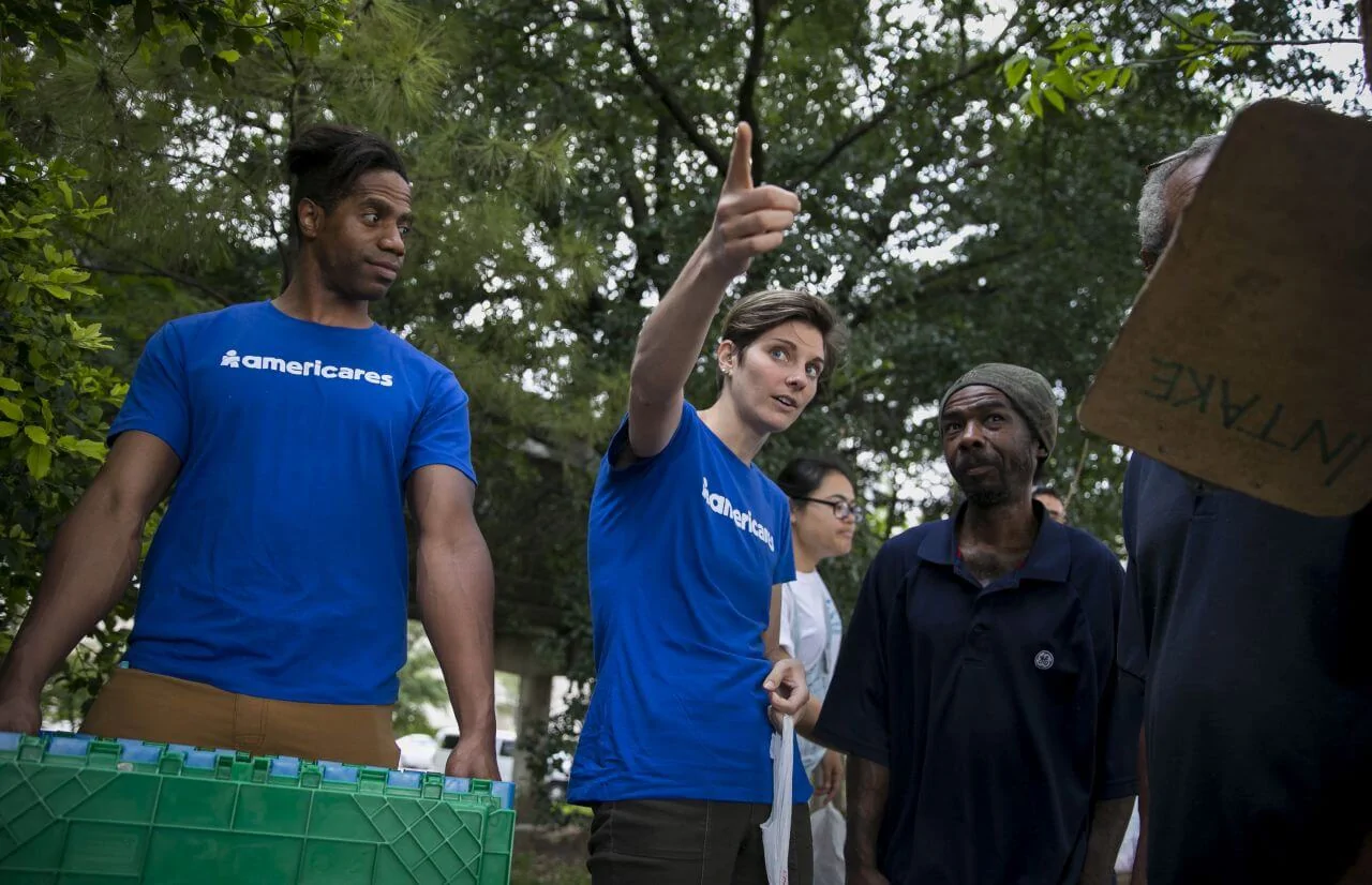 An Americares worker points beyond the camera while others look in that direction.