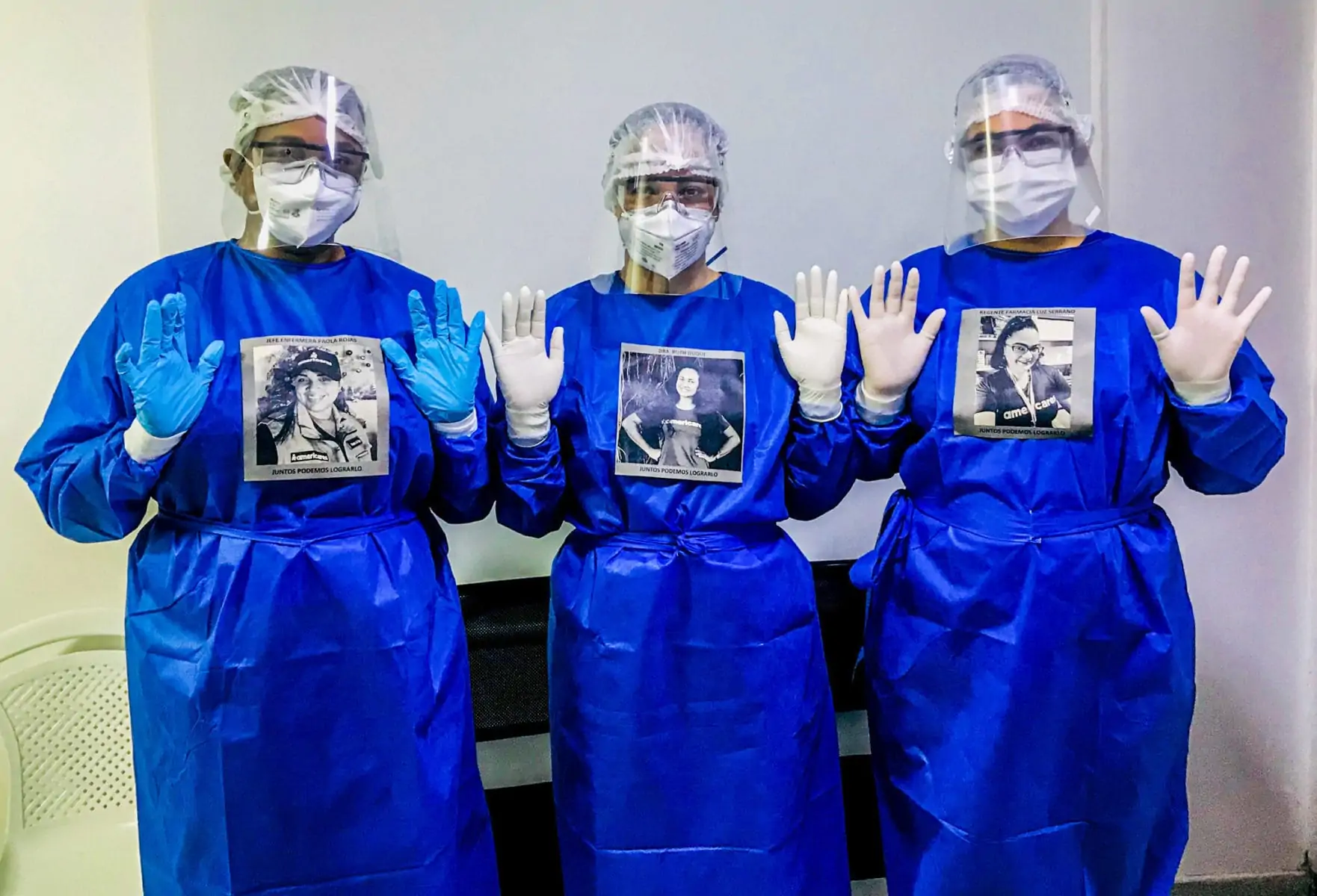 Three medical staff members in full protective gear with gown, gloves, face mask, face shield, and their name plates attached to their gowns..