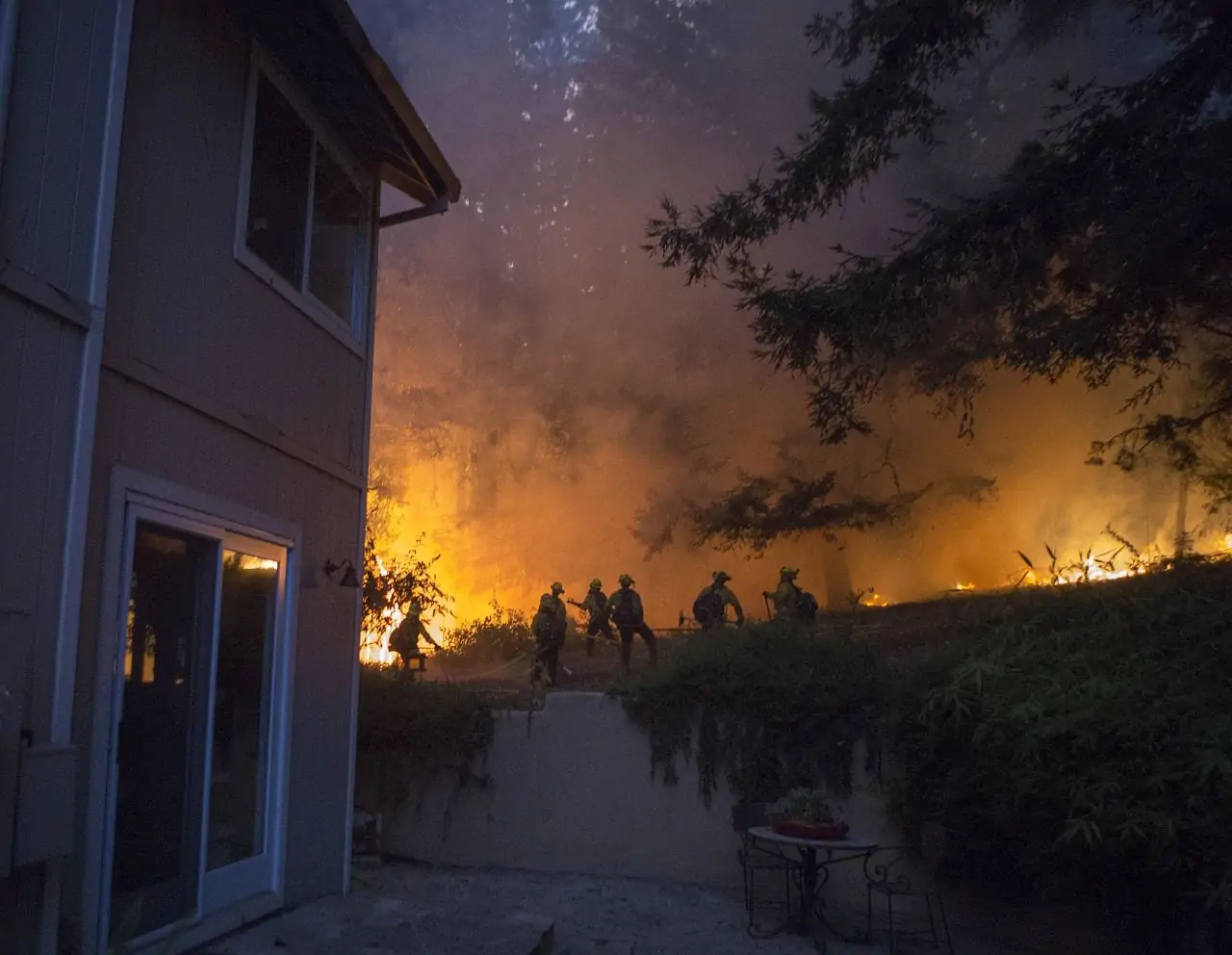 Fire outside of a home with firefighters combatting the blaze. Photo by David Royal
