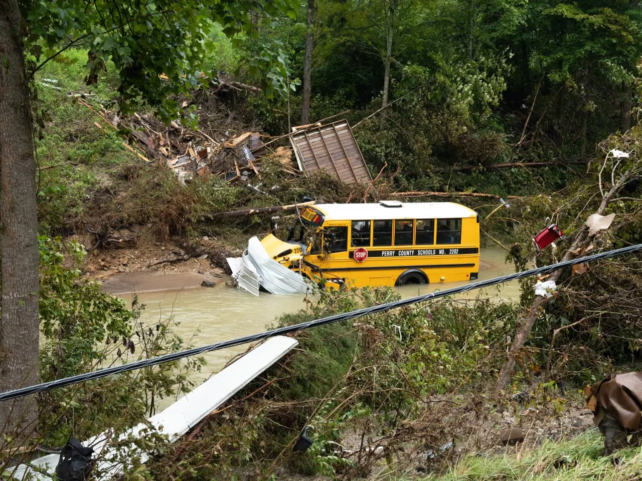 A Perry County yellow school bus sits in flood waters and surrounded by flood debris