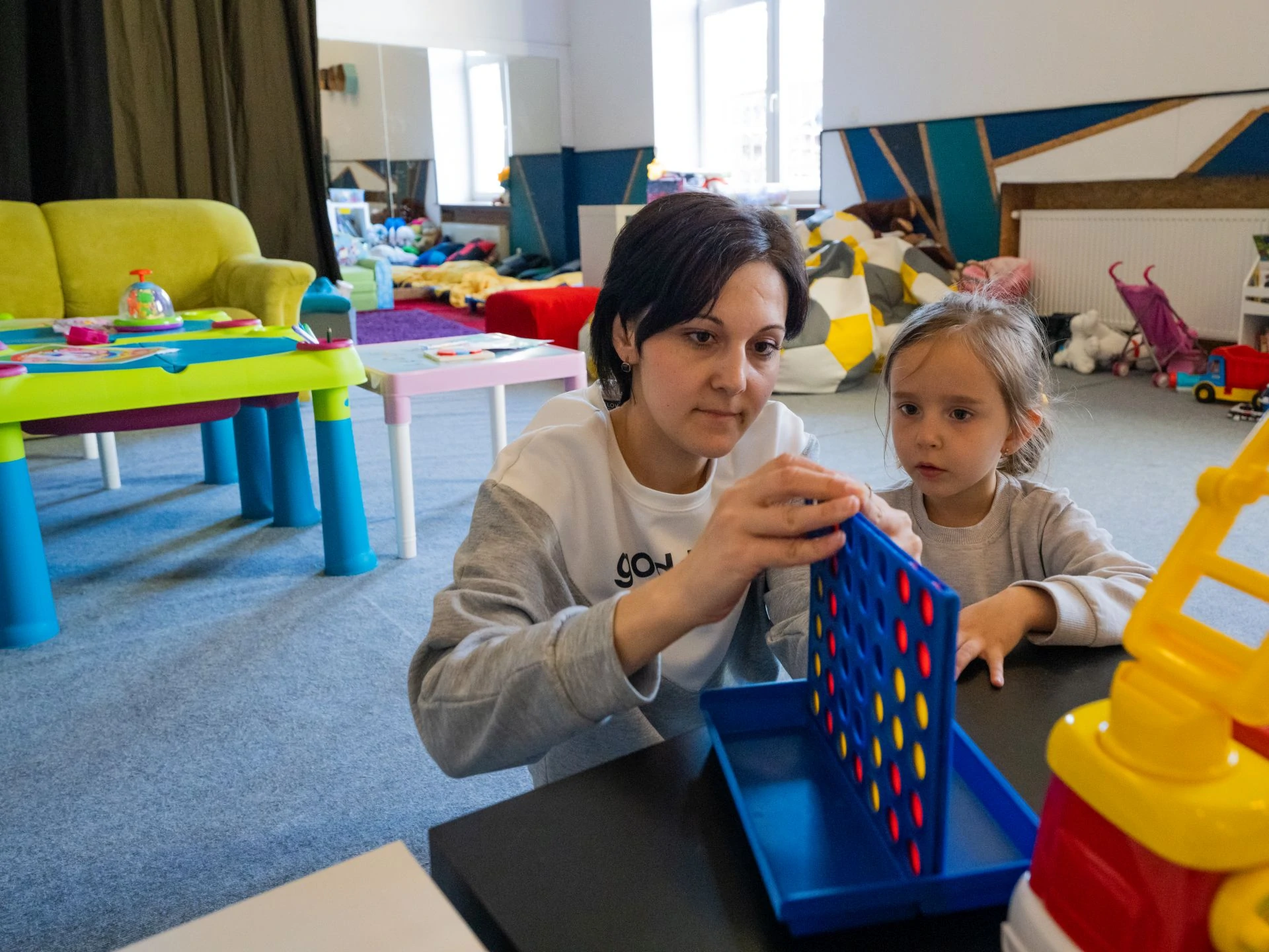 A mother plays a colorful game with her daughter in the JCC safe space in Krakow.