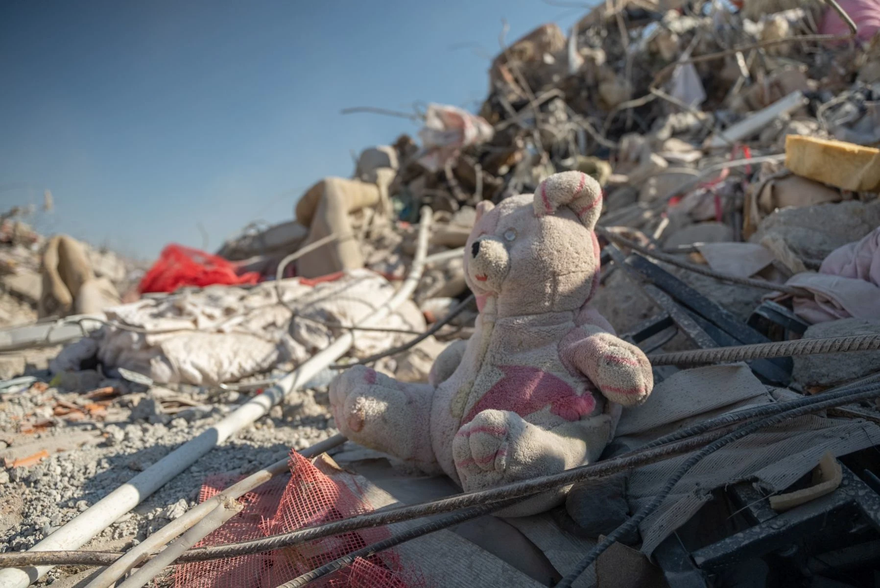 A teddy bear sits in the earthquake rubble in Turkey surrounded by cable, rebar and concrete remnants.