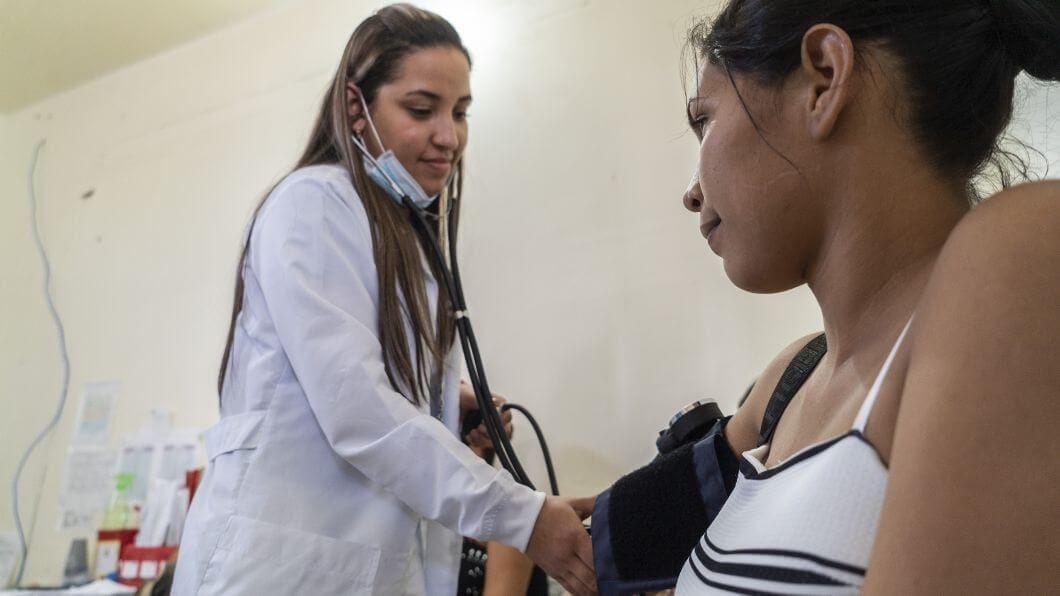 Colombia clinic health worker taking blood pressure of young woman