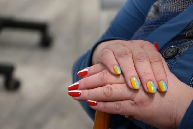 Oksana has her fingernails painted in the colors of Ukraine and of Poland. Nails on right hand are blue and yellow, on the left hand red and white.