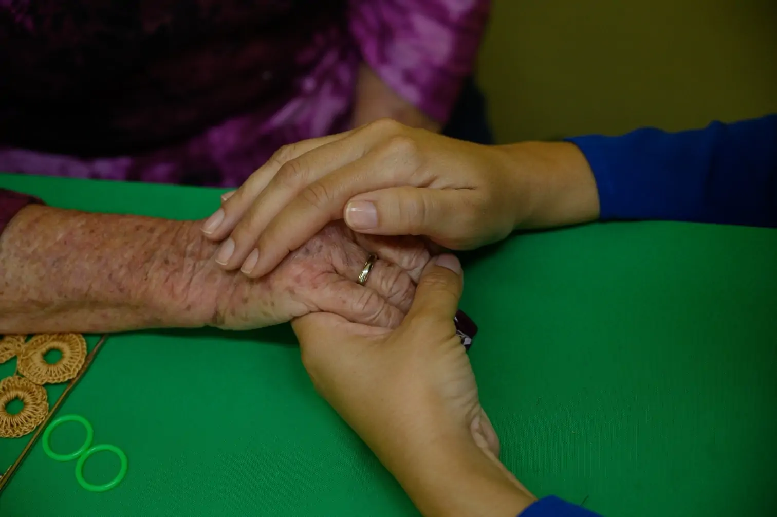 photo of an elderly person's hand being comforted by the hands of an Americares team member.
