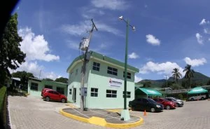 A fisheye lens view of part of the Americares family clinic in El Salvador. The building is green with cars parked on either side.
