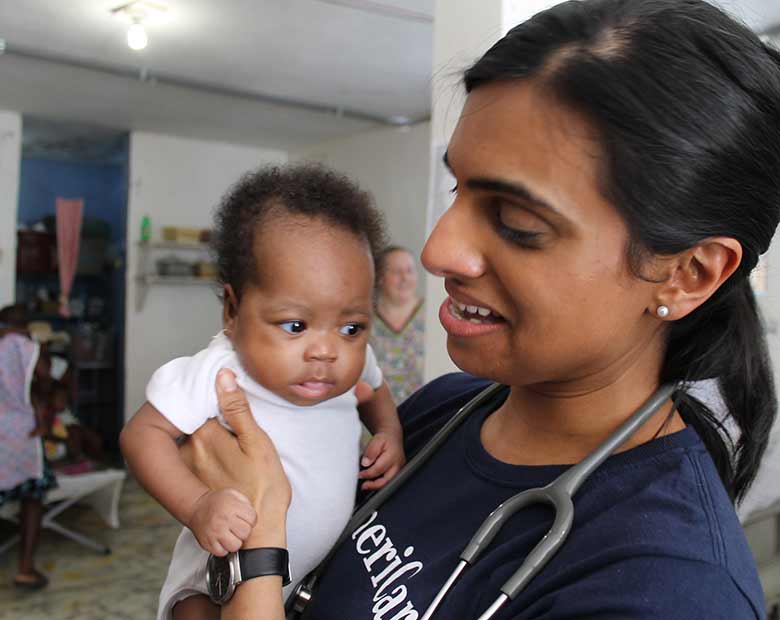 Dr. Julie holds an infant child in a temporary health facility.