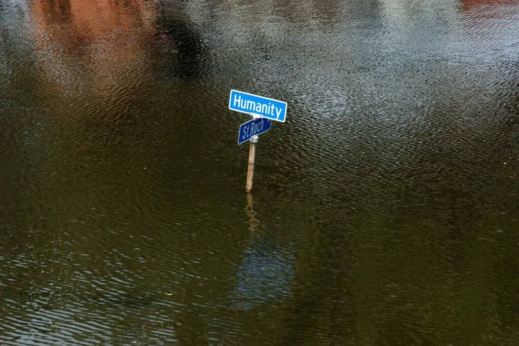 Street sign that says "Humanity" and "St. Roch" is surrounded by flood water.